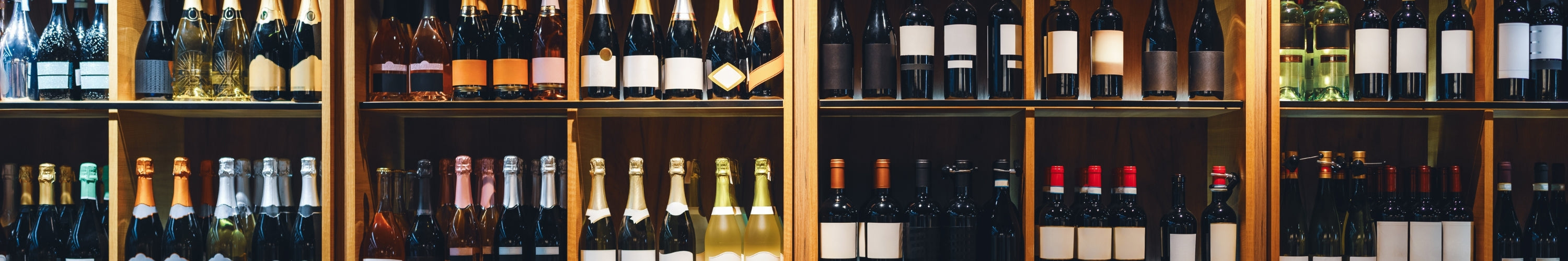 Front view of shelves displaying wine and champagne bottles in a liquor store.